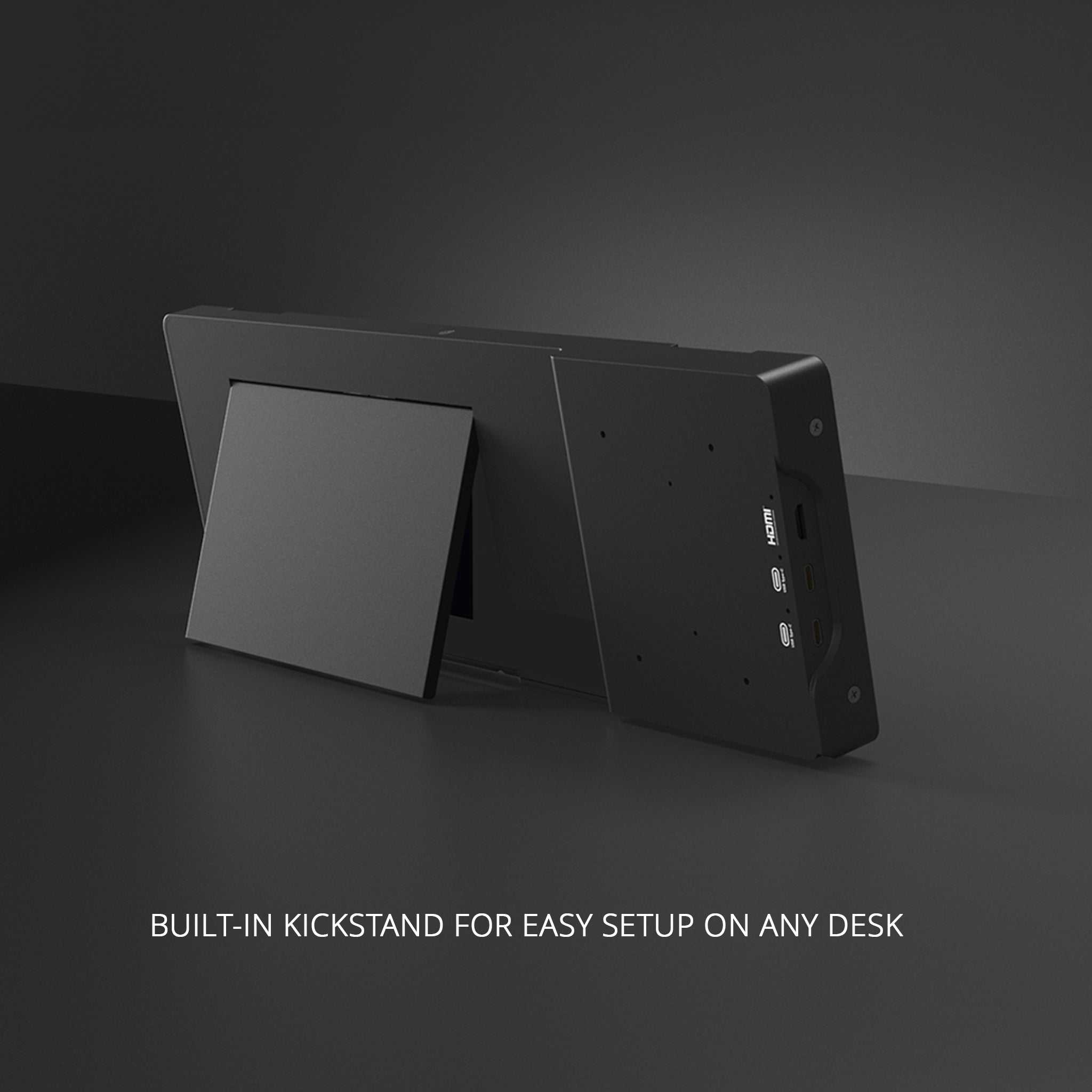 A black Prodesksim ProDeskSim Modular Display Unit with a built-in kickstand is set up on a dark surface, showing ports and buttons from the side. Text below reads: "BUILT-IN KICKSTAND FOR EASY SETUP ON ANY DESK.
