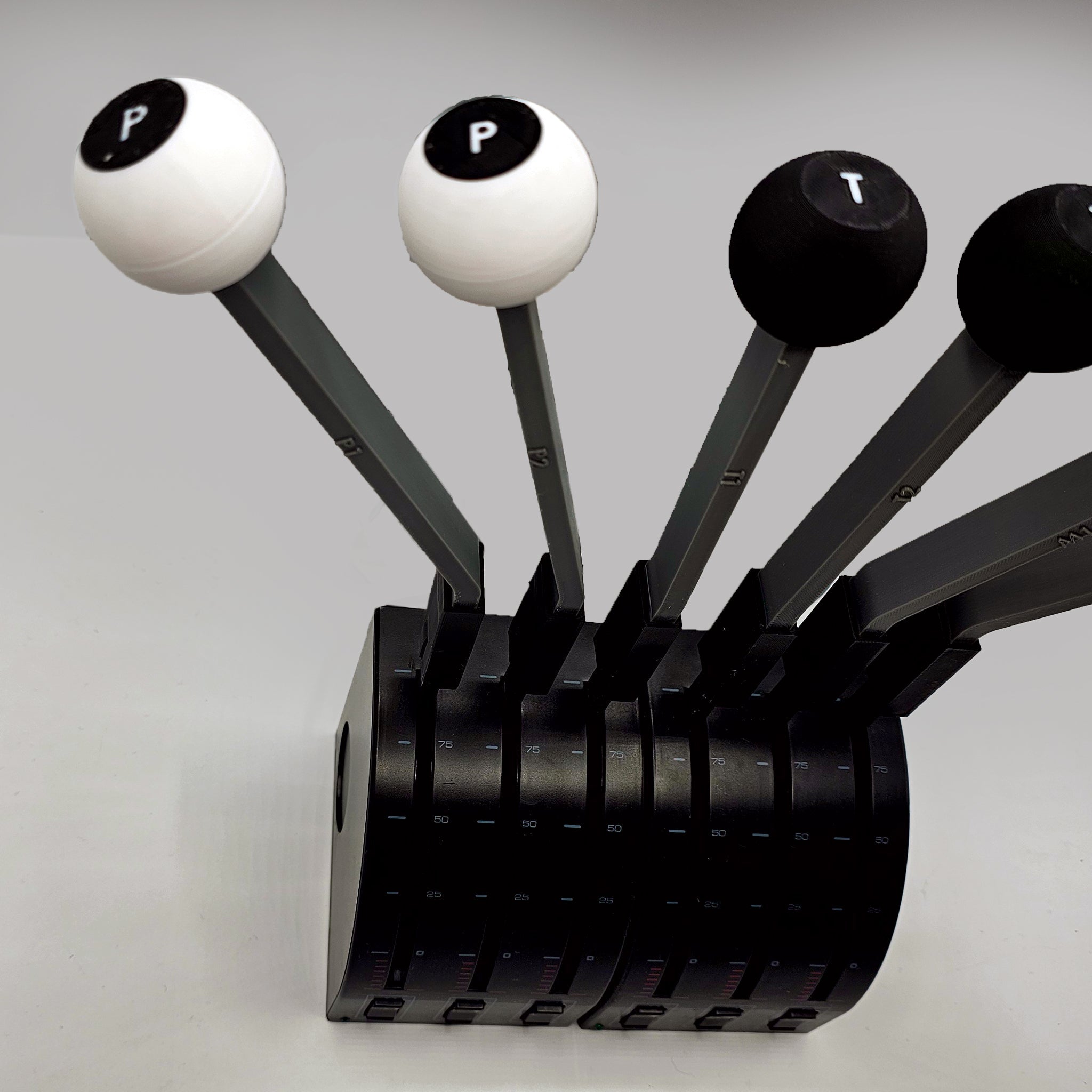 A full set of DC-3-inspired throttle quadrant handles by Prodesksim mirrors the elegance of a black and white knife block, housing five distinct handles. Each handle is skillfully marked with "P," "P," and "T," encapsulated in a cylindrical form with vertical slots against a light gray backdrop—a sophisticated tribute to flight simulation aficionados.