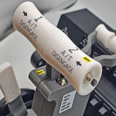 A close-up of the ProDeskSim Boeing 737 Advanced Full Package Addon/Modification for the Honeycomb Bravo throttle quadrant highlights two white levers marked "A/T Disengage" with arrows. An "INOP" sticker and a small switch labeled "AUTO THROTTLE DISENGAGE" are present, bringing to mind a flight simulation experience. The background is detailed with control panel elements.
