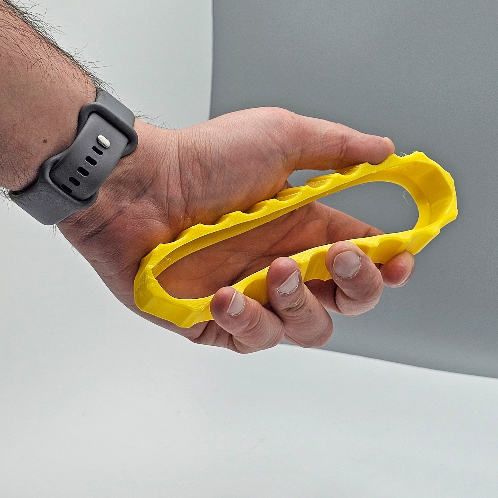 A person wearing a smartwatch holds a 1 Color Vibrant and Flexible Trim Wheel Cover for the Honeycomb Bravo Throttle Quadrant by Prodesksim, against a gray background, perfect for refining your flight simulation setup.