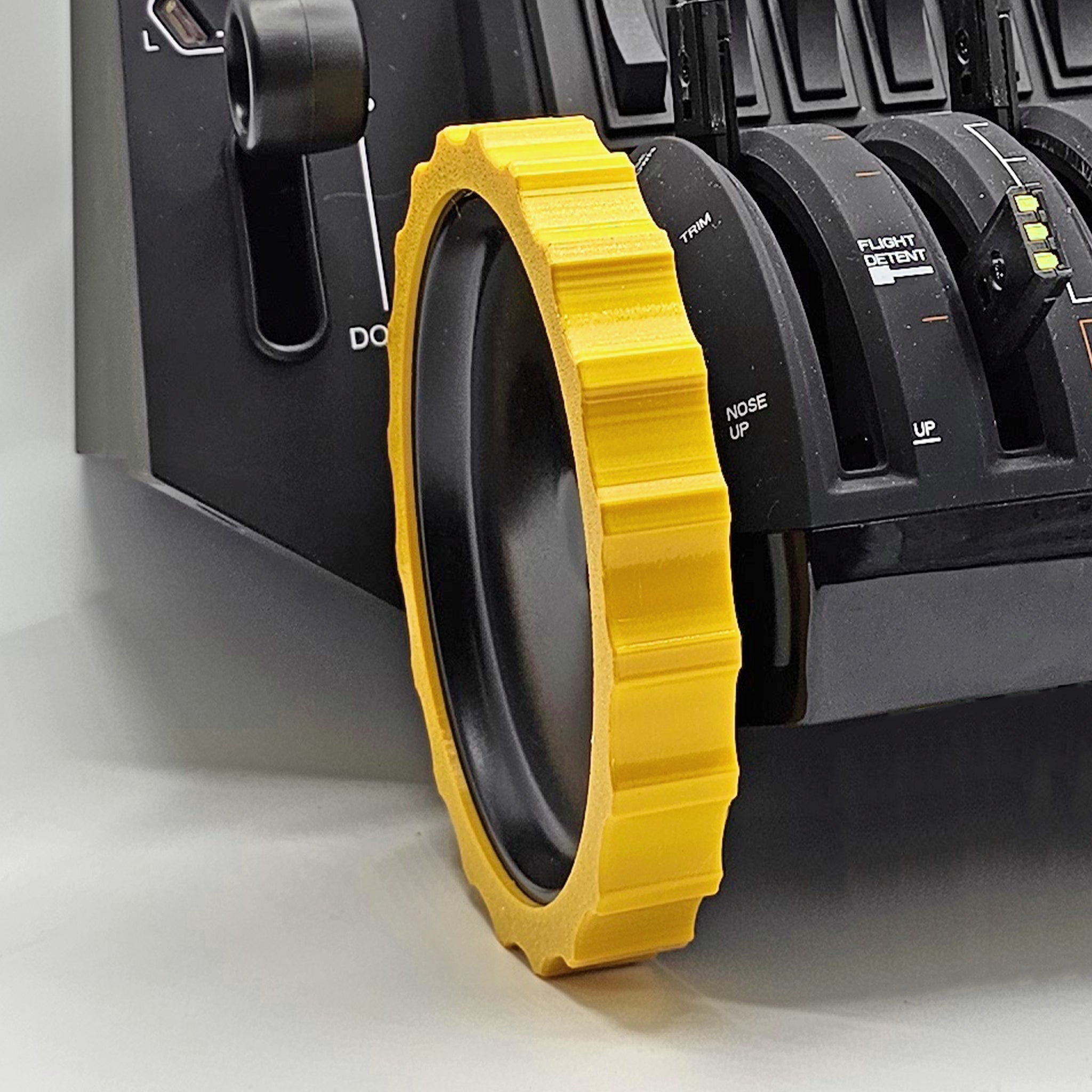 A close-up of a flight simulator control panel features a vibrant, flexible trim wheel cover in yellow from Prodesksim, enhancing your Honeycomb Bravo Throttle Quadrant with added realism and tactile detail amidst various switches and levers.