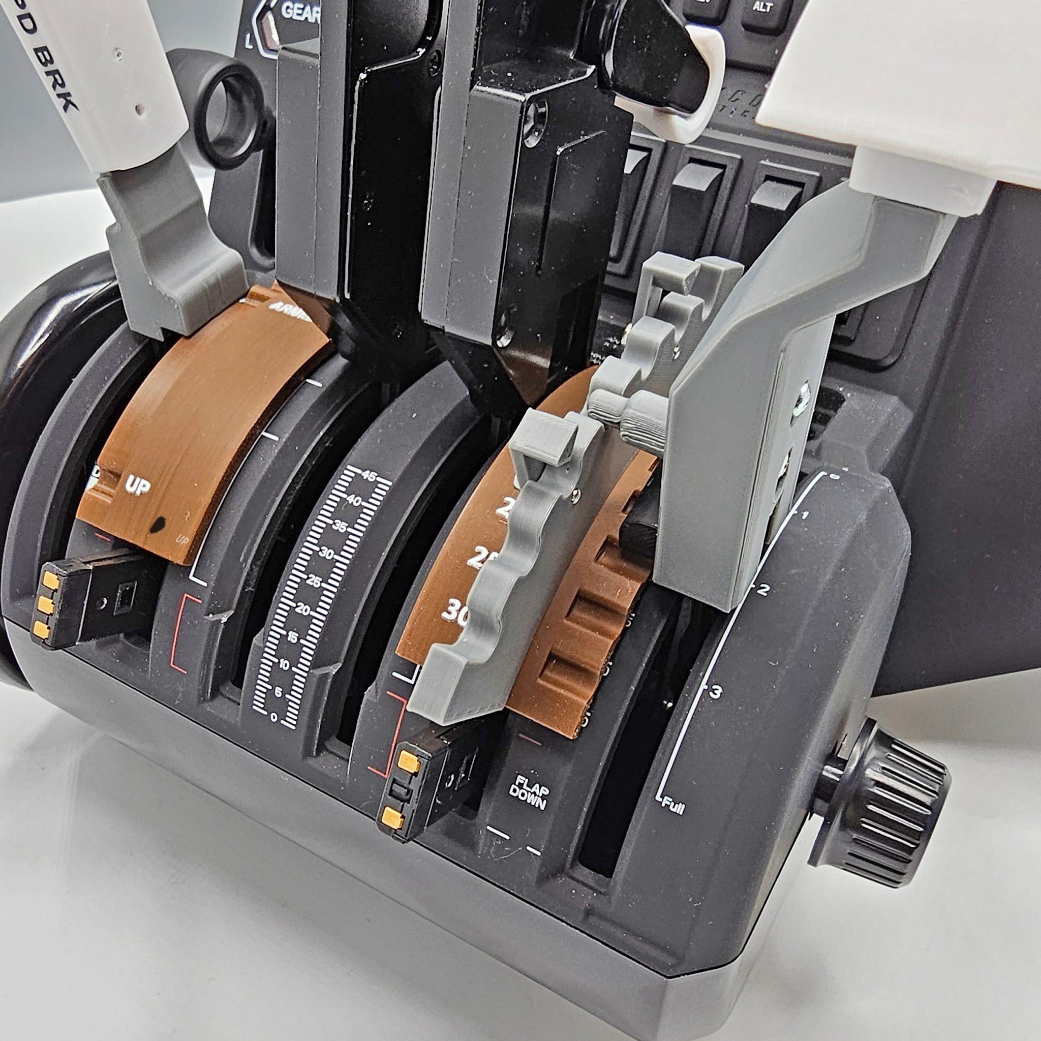 The image is a close-up of an aircraft throttle quadrant in a cockpit, showcasing the Prodesksim product: Boeing 777 Dual Action Detent/Spring mechanism flaps and Detent realistic speed brake Professional addon for HoneyComb Bravo throttle/VR. It features two marked throttle levers flanked by various switches and controls, with additional cockpit instruments softly blurred in the background.