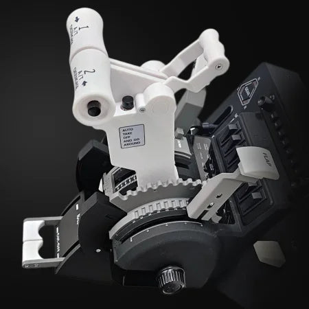 A close-up of a black and white mechanical film splicer with labeled levers, dials, and slots for loading film reels, reminiscent of the precise controls on the Prodesksim New ProDeskSim 737 Ultra Full Package Addon, set against a dark background.