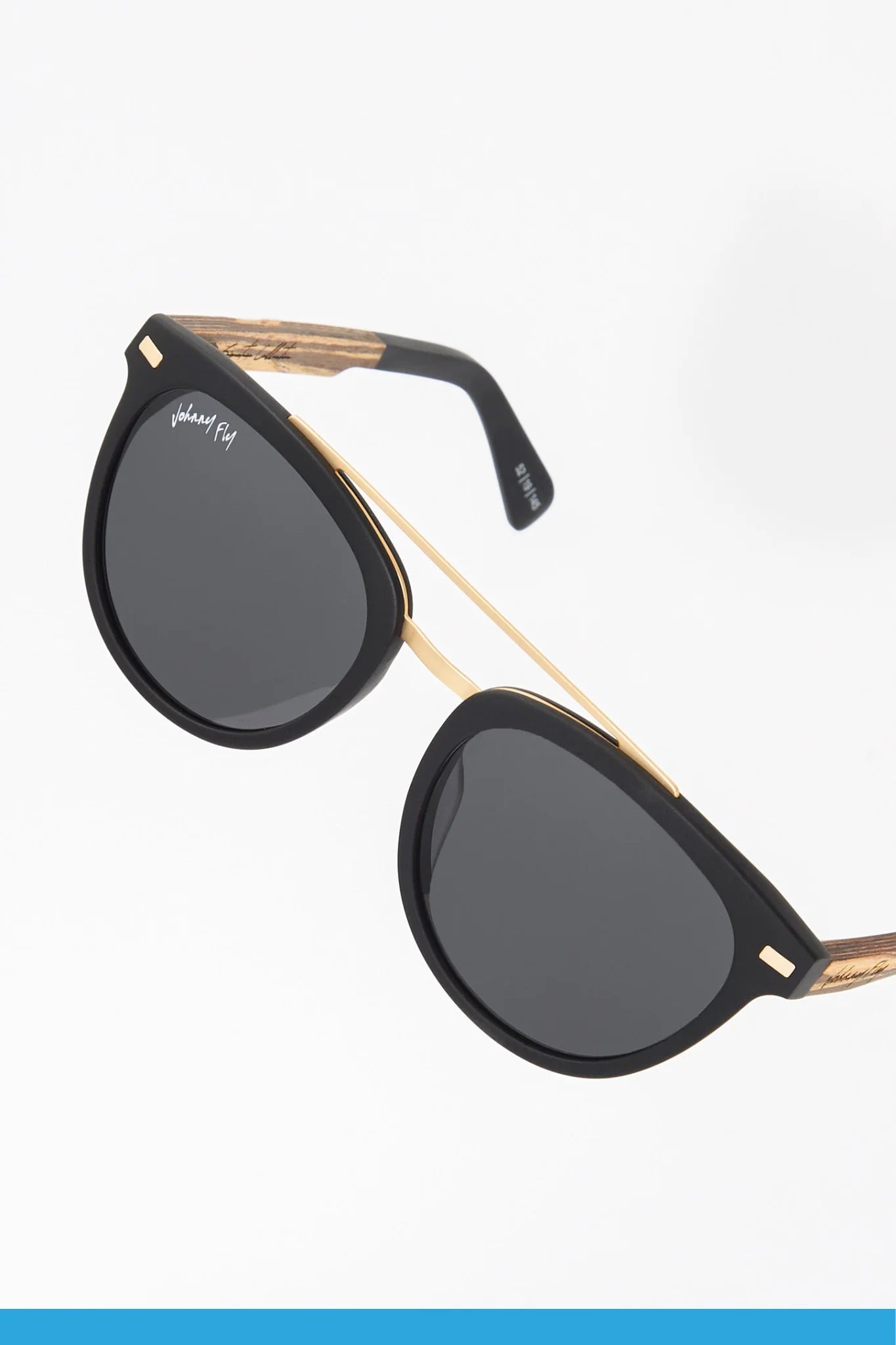 Introducing the Captain sunglasses by Johnny Fly: a stylish pair featuring a sleek acetate front section with gold accents and polarized lenses. The arms boast a textured wood-like pattern, adding a hint of natural charm.