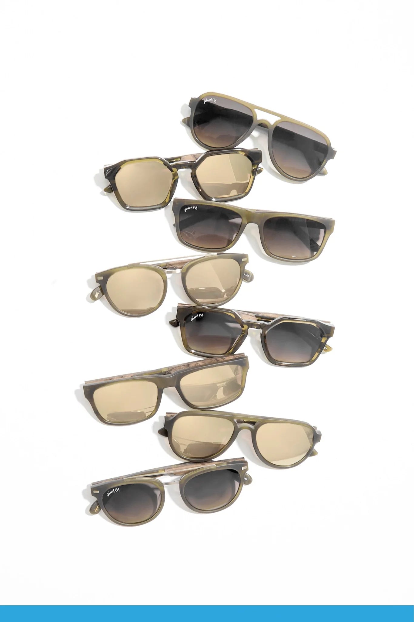 A set of nine pairs of Captain sunglasses by Johnny Fly, showcasing wooden arms and polarized lenses, laid out on a white background. The collection includes various shapes with tinted lenses, and frames in neutral tones such as brown and olive.