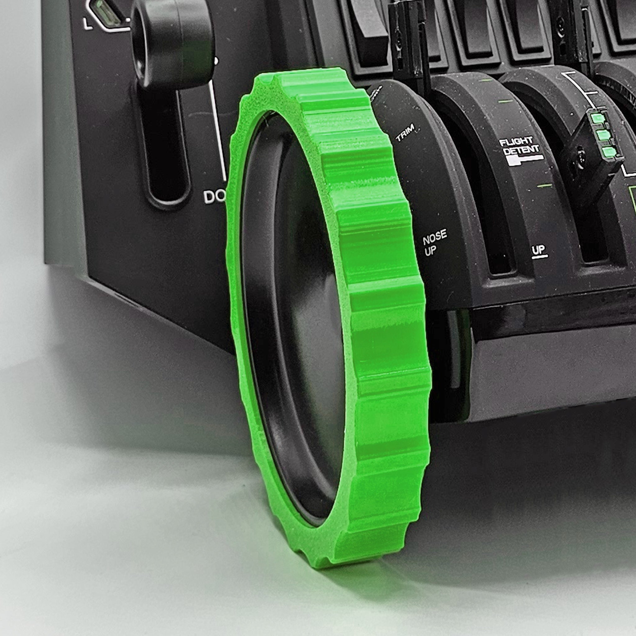A close-up of the Honeycomb Bravo Throttle Quadrant, crafted for flight simulation, showcases black and green levers labeled "Down," "Nose Up," and "UP." Adding a striking contrast to the black housing is a bright green Prodesksim 1 Color Vibrant and Flexible Trim Wheel Cover with ridged edges.