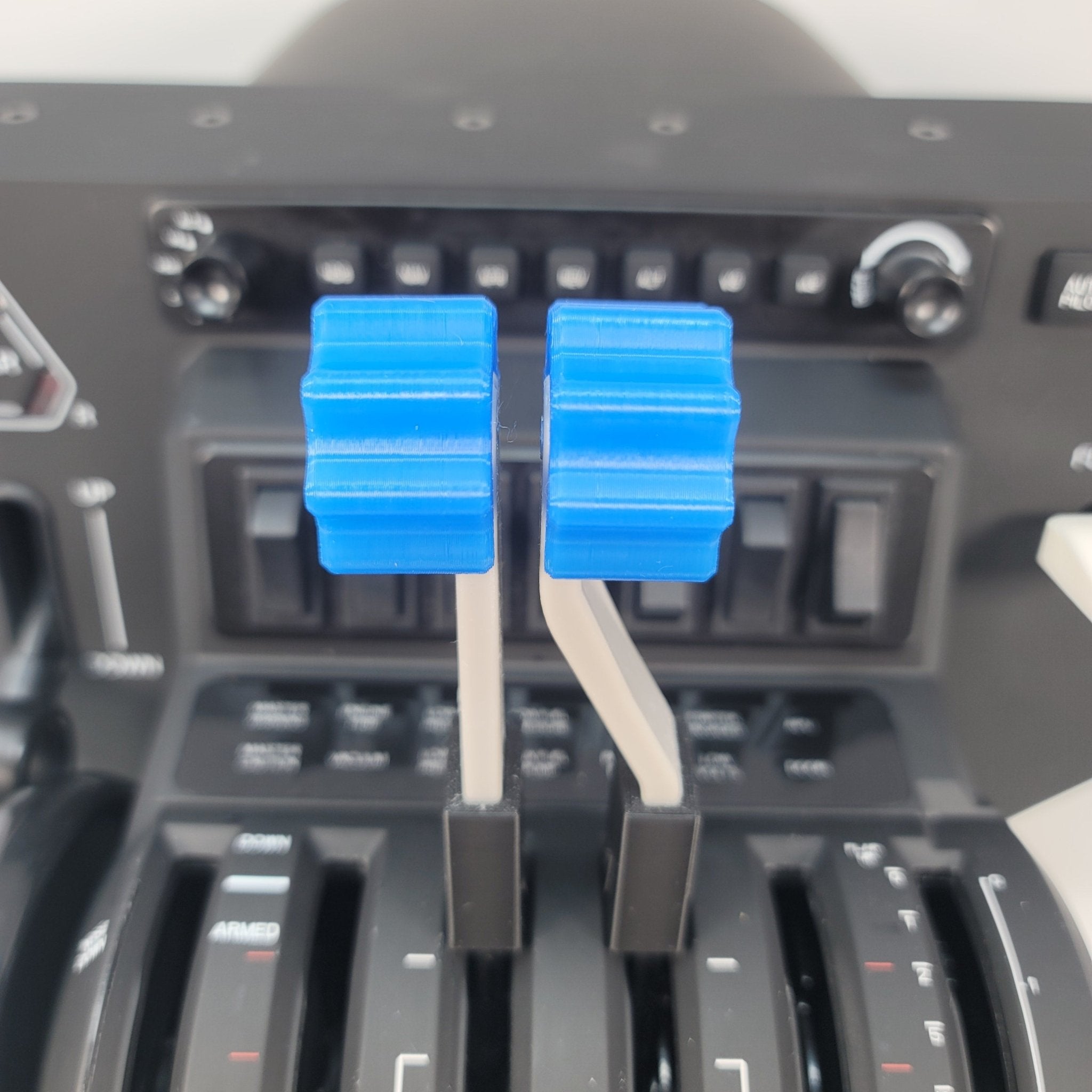 Close-up of a Prodesksim Honeycomb Bravo G58 Baron twin engine piston throttle quadrant with realistic throttle, fuel mixture, and prop pitch handles, featuring two blue levers in the center surrounded by various switches and indicators. This scene showcases part of the cockpit control panel, highlighting the perfect addon for your flight simulation upgrade.