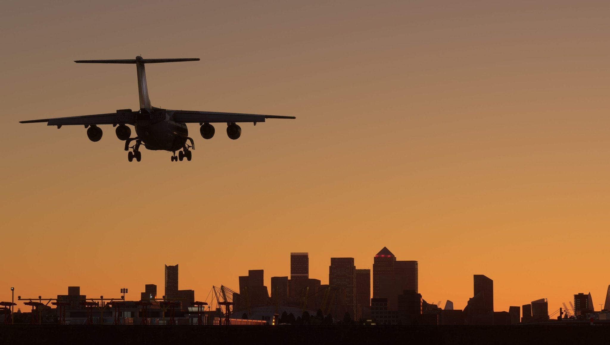 A silhouette of an airplane from the Just Flight BAE-146 Professional for MSFS2020 series lands at an airport against an orange sunset backdrop. In the distance, the skyline of a city looms with various skyscrapers outlined against the sky, reminiscent of a stunning Microsoft Flight Simulator 2020 experience.