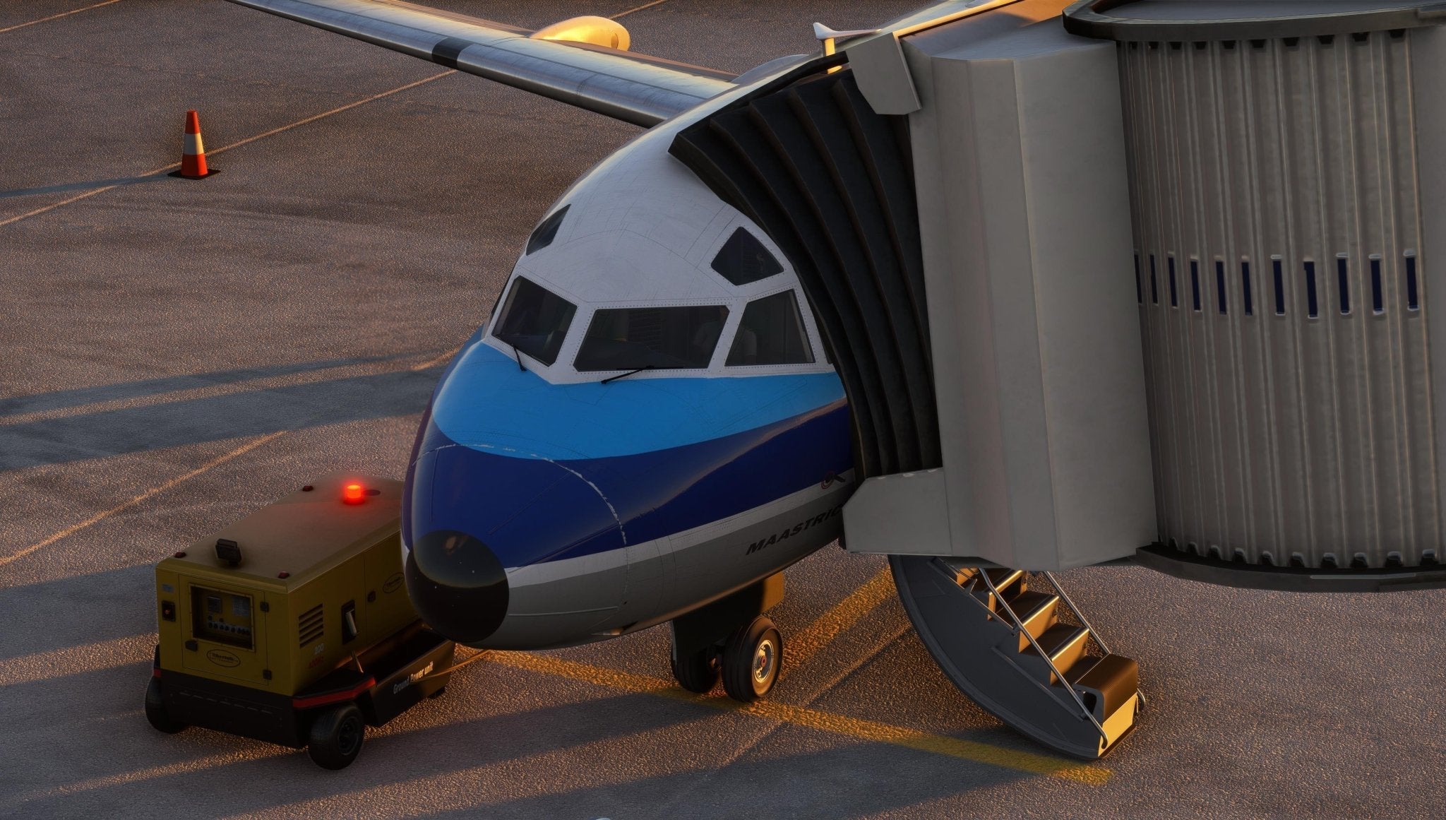 A Just Flight Fokker-28 Professional for MSFS2020, part of the renowned Just Flight lineup, is connected to a jet bridge at an airport gate. Seen from the front, the passenger airplane displays a blue and white color scheme, with a ground power unit positioned nearby.