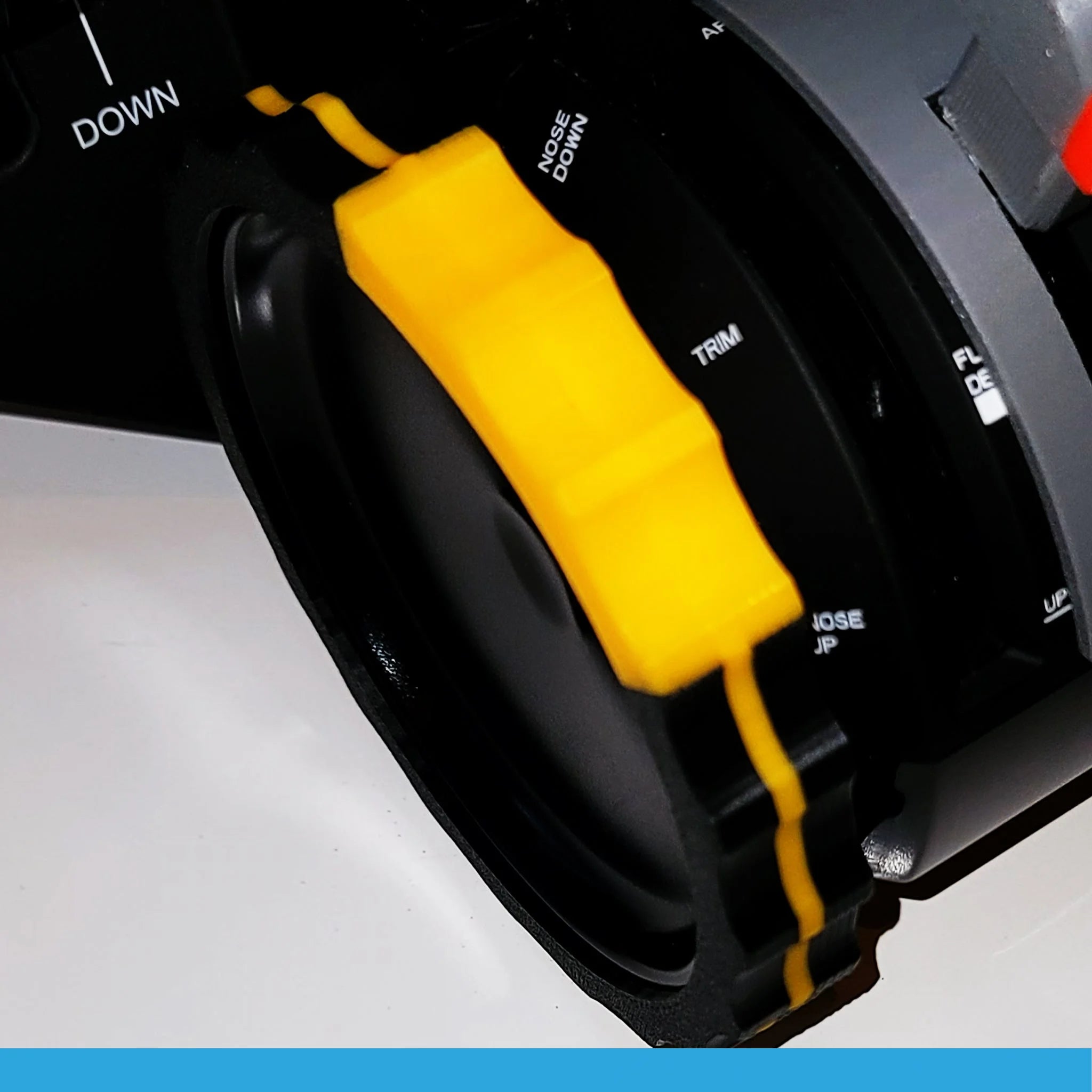 Close-up of a black and yellow control knob on a Honeycomb Bravo Throttle Quadrant, featuring labels such as "DOWN," "TRIM," and "NOSE DOWN," with the premium 2 Color TRIMER by Prodesksim. The knob, equipped with a textured grip ideal for flight simulation, is mounted on a smooth surface.