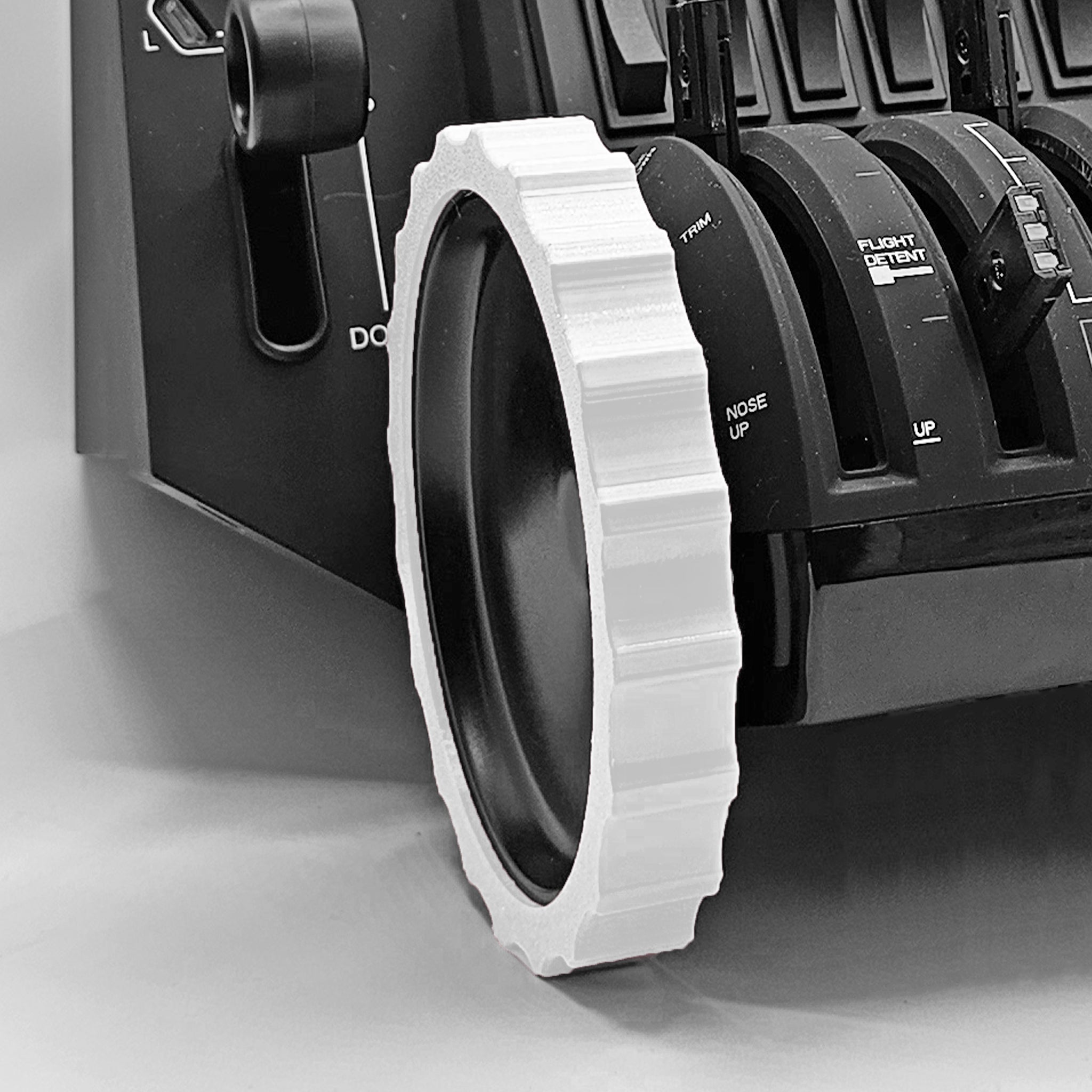 Close-up of a Prodesksim 1 Color Vibrant and Flexible Trim Wheel Cover in white, seamlessly attached to a black mechanical device similar to the Honeycomb Bravo Throttle Quadrant for flight simulation. The cover features a ridged edge encircling a circular component. The device is equipped with levers labeled "PLY/CNT," "TRIM," and "FLIGHT DECK RFY.
